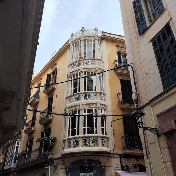Fachada ocre con una galería acristalada en cada planta, vista desde abajo