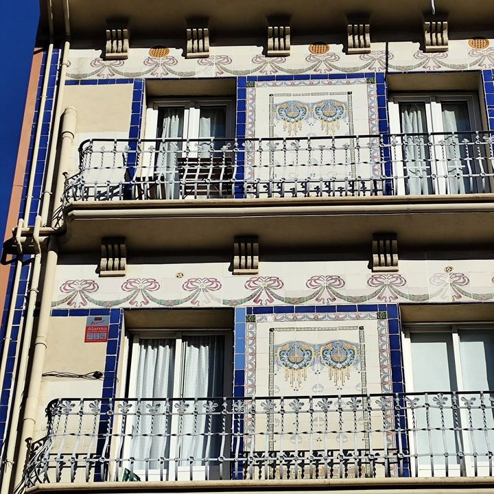 Balcones con barandilla de hierro y azulejos azules en la fachada