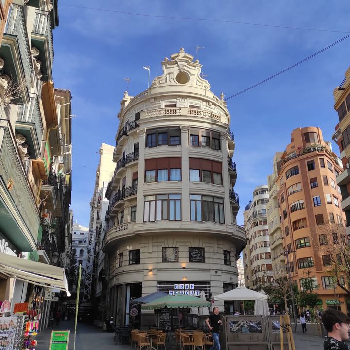 Edificio de esquina redondeada con cúpula, en una calle comercial