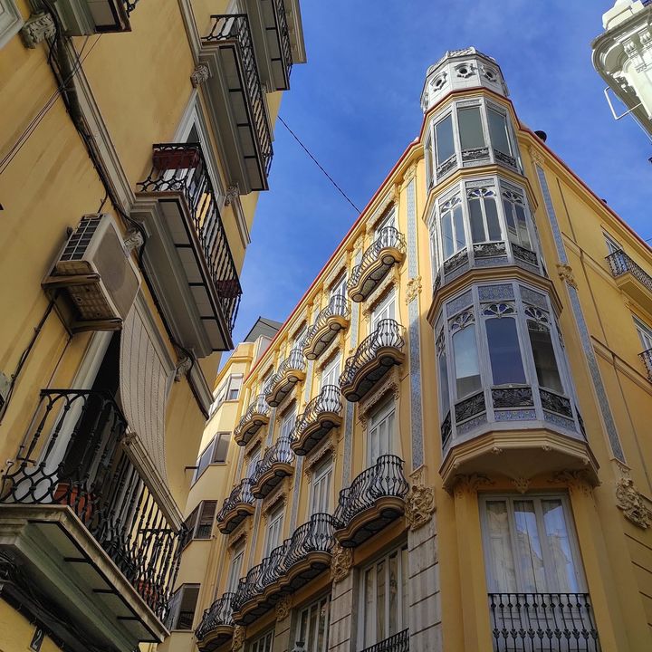 Edificio amarillo con miradores de esquina, visto desde abajo