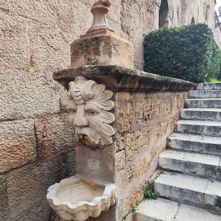 Fuente de piedra con un mascarón junto a una escalera
