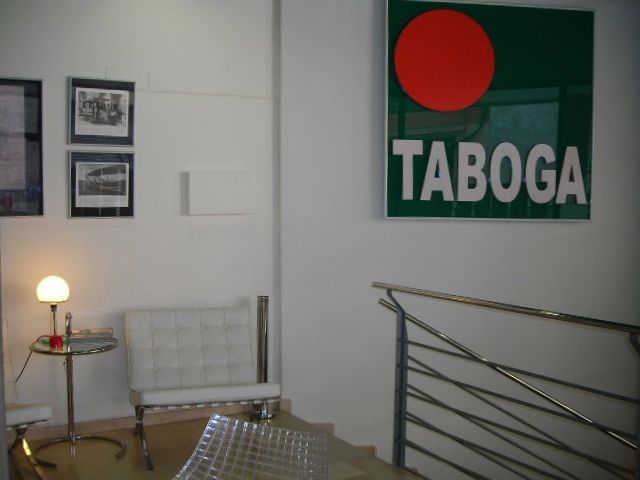 El cartel verde con el círculo rojo y la palabra TABOGA en la pared de la oficina